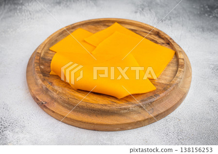 Bright sliced cheese on wooden board beside knife top view dairy ingredient for cooking menus and food design Bright sliced cheese on wooden board beside knife top view dairy ingredient for cooking menus and food design 138156253