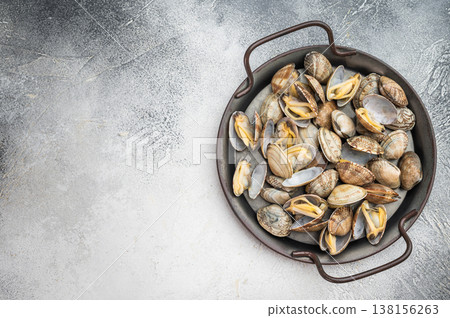 Italian vongole clams arranged in rustic metal pan. Fresh seafood dish with shells on light background, top view. 138156263