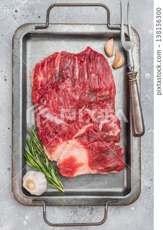Raw beef brisket on metal tray with garlic and rosemary, top view cooking preparation scene with copy space 138156300