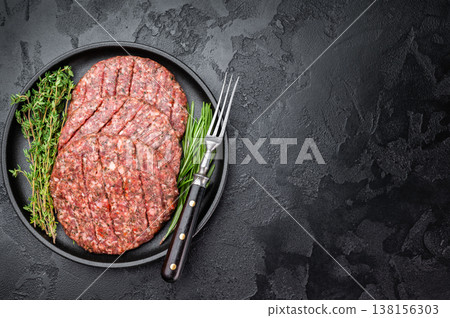 Fresh raw minced beef and lamb cutlets in plate with herbs. Flat lay on dark stone background for barbecue themes. Fresh raw minced beef and lamb cutlets in plate with herbs. Flat lay on dark stone background for barbecue themes. 138156303
