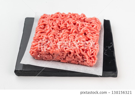 Raw minced beef ground meat portion on parchment paper on slate board Raw minced beef ground meat portion on parchment paper on slate board 138156321