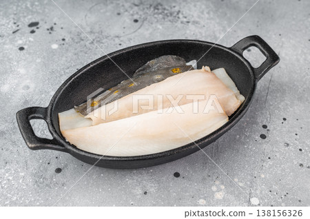 Fresh dab flatfish fillets with herbs and garlic in cast iron pan, raw seafood ingredient for healthy cooking on light textured background Fresh dab flatfish fillets with herbs and garlic in cast iron pan, raw seafood ingredient for healthy cooking on light textured background 138156326