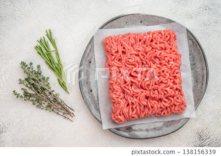 Raw minced pork and beef ground meat portion on parchment paper on plate isolated on light background with copy space 138156339