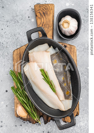 Fresh dab flatfish fillets with herbs and garlic in cast iron pan, raw seafood ingredient for healthy cooking on light textured background 138156341