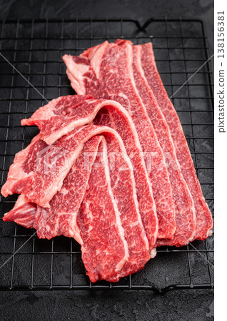 Luxury marbled beef slices resembling wagyu texture on grill rack, raw angus bacon cut on dark background, gourmet meat concept Luxury marbled beef slices resembling wagyu texture on grill rack, raw angus bacon cut on dark background, gourmet meat concept 138156381