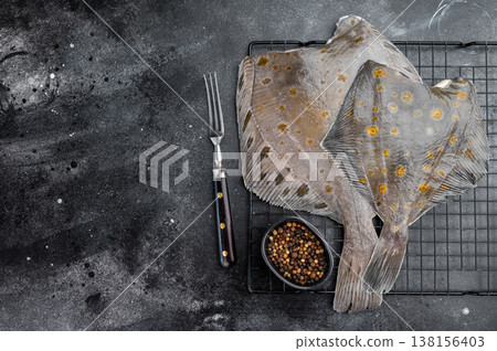 Raw flounder flatfish with spotted skin on rack with pepper on dark background fresh seafood ingredient Raw flounder flatfish with spotted skin on rack with pepper on dark background fresh seafood ingredient 138156403
