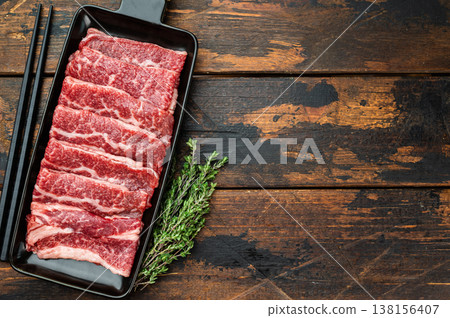 Marbled beef slices prepared for Korean BBQ grilling, raw premium meat on slate board with chopsticks, dark background 138156407