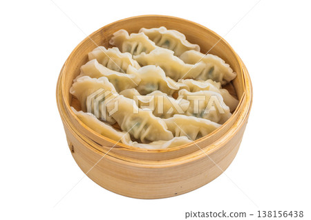 Soft dough dumplings gyoza filled with vegetables and meat presented in bamboo basket ideal for Asian food marketing menus and stock imagery. 138156438