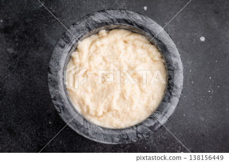 Dark and moody food photo. Creamy horseradish sauce in a marble mortar and pestle, set on a textured slate background. Copy space. Dark and moody food photo. Creamy horseradish sauce in a marble mortar and pestle, set on a textured slate background. Copy space. 138156449