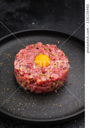 Beef tartare with yolk on black dish against dark backdrop great for gourmet cooking protein rich meals and high quality food photography. 138156460