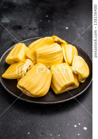 Sweet, golden yellow jackfruit pods (bulbs) served in a black plate on a dark stone background. Exotic tropical fruit with copy space 138156480