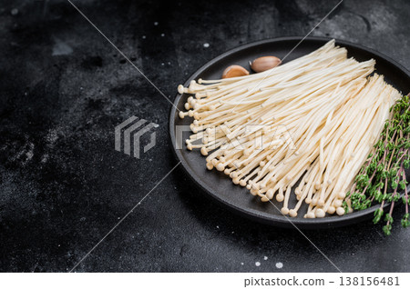 Top view of raw Enokitake on a dark textured surface. High-contrast, moody food photography for healthy cooking. Top view of raw Enokitake on a dark textured surface. High-contrast, moody food photography for healthy cooking. 138156481