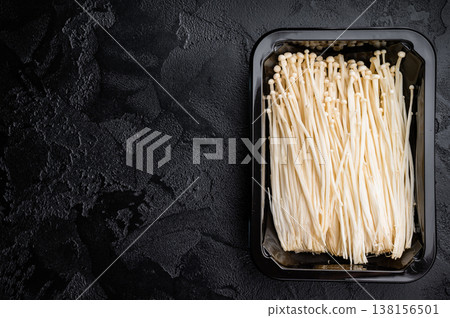 Fresh Enoki mushrooms in a black tray on a textured dark background. Excellent copy space for text, recipes, or graphic design elements. 138156501