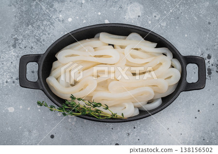 Fresh calamari rings in cast iron bowl with thyme on textured gray background ideal seafood ingredient for gourmet cooking. 138156502