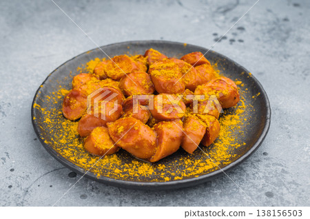 Hot sausage currywurst with curry ketchup and spices on dark dish suitable for fast food marketing snack visuals and premium food photography. Hot sausage currywurst with curry ketchup and spices on dark dish suitable for fast food marketing snack visuals and premium food photography. 138156503