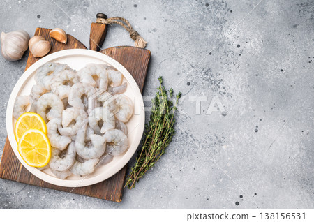 Raw shrimp prawn with lemon, garlic, and thyme on a textured grey background. Top view of seafood preparation with copy space. Raw shrimp prawn with lemon, garlic, and thyme on a textured grey background. Top view of seafood preparation with copy space. 138156531