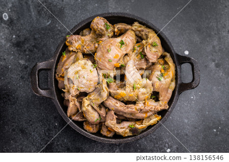 Cooked stew from poultry gizzards with herbs in cast iron pan on dark stone background perfect for rustic food photography and menu design. Cooked stew from poultry gizzards with herbs in cast iron pan on dark stone background perfect for rustic food photography and menu design. 138156546