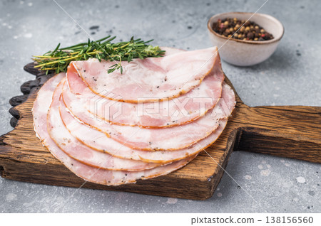 Slices of Italian Pancetta Arrotolata with rosemary on a wooden board and vintage fork. Light concrete background. Slices of Italian Pancetta Arrotolata with rosemary on a wooden board and vintage fork. Light concrete background. 138156560