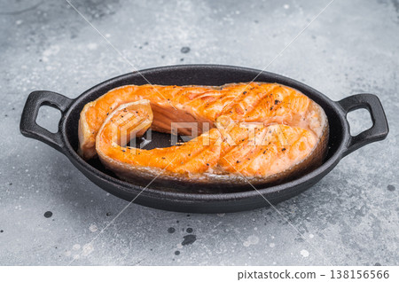 Healthy roasted redfish salmon steak seasoned and served in cast iron with thyme and citrus displayed on a rustic board over a gray background. 138156566