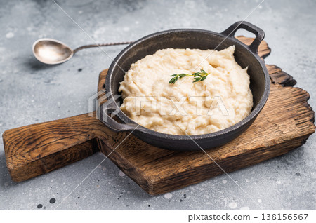 Modern food composition. Creamy horseradish dip with thyme in a cast iron pot on a wooden board. Light gray background. Copy space. 138156567