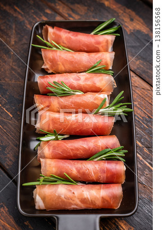 Delicious dry-cured Jamon pork meat served with herbs. Classic overhead view, perfect for a culinary theme. Delicious dry-cured Jamon pork meat served with herbs. Classic overhead view, perfect for a culinary theme. 138156568