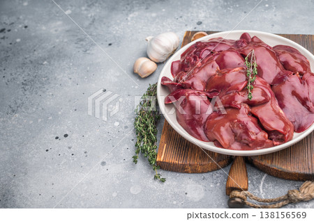 Close-up of fresh chicken liver with a knife and herbs, displayed on a textured gray surface. Ideal for food blog visuals. Close-up of fresh chicken liver with a knife and herbs, displayed on a textured gray surface. Ideal for food blog visuals. 138156569