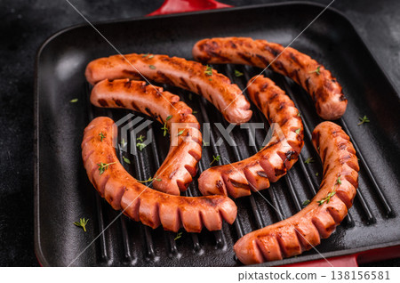 Top view of six cooked sausages with perfect grill marks and thyme in a red handle pan. Food background with copy space. 138156581