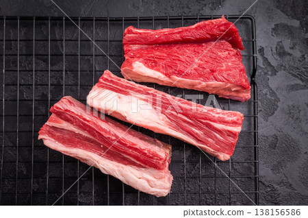 Premium raw beef short ribs with thyme and pink peppercorns on a black wire rack. Perfect for grilling or slow cooking. Premium raw beef short ribs with thyme and pink peppercorns on a black wire rack. Perfect for grilling or slow cooking. 138156586