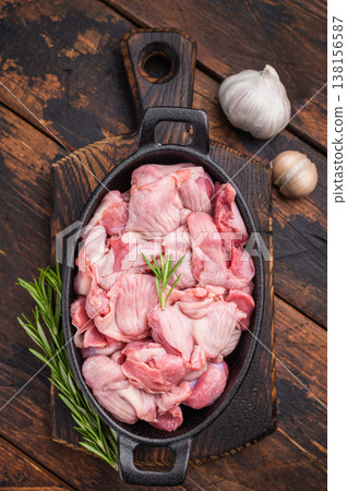 Fresh poultry offal in a cast iron dish, accompanied by aromatic herbs and garlic on a wooden surface Fresh poultry offal in a cast iron dish, accompanied by aromatic herbs and garlic on a wooden surface 138156587