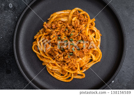 Delicious ragu pasta with herbs and parmesan on a dark stone backdrop, styled with vintage fork and fresh thyme, top view. Delicious ragu pasta with herbs and parmesan on a dark stone backdrop, styled with vintage fork and fresh thyme, top view. 138156589