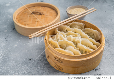 Steamed Asian dumplings mandu served in bamboo steamer on concrete background with chopsticks perfect for dim sum menus. Steamed Asian dumplings mandu served in bamboo steamer on concrete background with chopsticks perfect for dim sum menus. 138156591