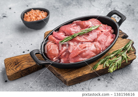 Raw quail breast fillets with rosemary and pink salt in a cast iron pan on a wooden board. Rustic gourmet food preparation. Raw quail breast fillets with rosemary and pink salt in a cast iron pan on a wooden board. Rustic gourmet food preparation. 138156616