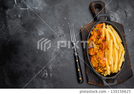 Traditional currywurst, wurst topped with curry spice and fries on dark stone surface great for street food themes and high quality food photography. Traditional currywurst, wurst topped with curry spice and fries on dark stone surface great for street food themes and high quality food photography. 138156625