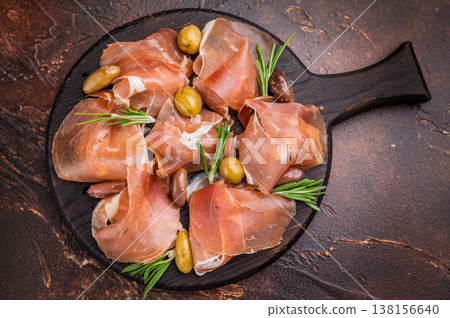 Gourmet Italian Prosciutto with fresh rosemary on a dark round plate. Gourmet Italian Prosciutto with fresh rosemary on a dark round plate. 138156640