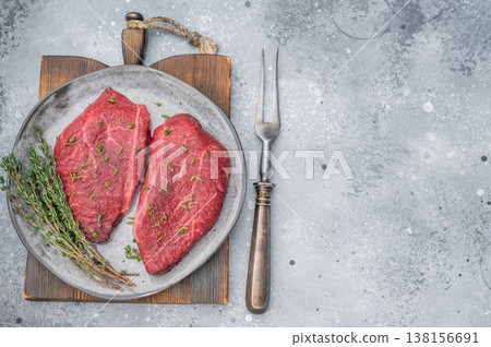 Raw Wagyu Top Blade chuck steaks with thyme on gray ceramic plate over light concrete background perfect for gourmet butcher and culinary stock photography. Raw Wagyu Top Blade chuck steaks with thyme on gray ceramic plate over light concrete background perfect for gourmet butcher and culinary stock photography. 138156691