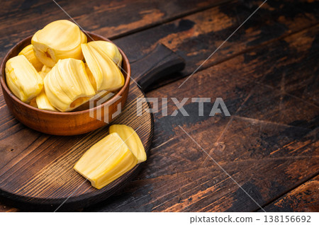 Sweet, golden jackfruit pods (bulbs) in a wooden bowl on a rustic dark wood table. Tropical fruit snack with copy space. Sweet, golden jackfruit pods (bulbs) in a wooden bowl on a rustic dark wood table. Tropical fruit snack with copy space. 138156692