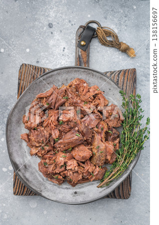 Hearty braised moose venison stew on a grey background, tender shredded game meat cooked slow for deep savory taste and rustic appeal. 138156697