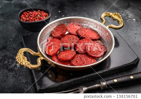 Fried Turkish sucuk (sujuk) in a copper pan on a dark stone background with copy space. Traditional breakfast. 138156701