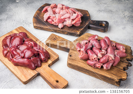Assorted raw giblets including hearts, liver, and gizzards on vintage wooden boards, organic poultry cooking concept. Assorted raw giblets including hearts, liver, and gizzards on vintage wooden boards, organic poultry cooking concept. 138156705