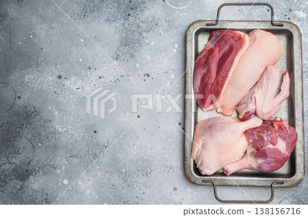 Raw duck parts breast wing and thigh on metal tray over grey stone background ideal for gourmet poultry cooking and stock images. Raw duck parts breast wing and thigh on metal tray over grey stone background ideal for gourmet poultry cooking and stock images. 138156716
