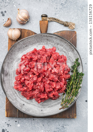 Fresh raw minced beef with thyme on a gray plate over concrete background ideal for recipe layouts negative space and food stock images. Fresh raw minced beef with thyme on a gray plate over concrete background ideal for recipe layouts negative space and food stock images. 138156729