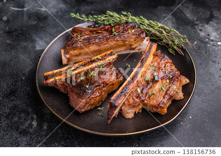 Gourmet glazed beef short ribs with fresh rosemary. Deep rusty brown background with ample negative space. Gourmet glazed beef short ribs with fresh rosemary. Deep rusty brown background with ample negative space. 138156736