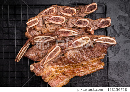 Grilled beef short ribs (Flanken/Galbi) on a black background. Served with pink Himalayan salt. Top view, dramatic lighting. 138156738