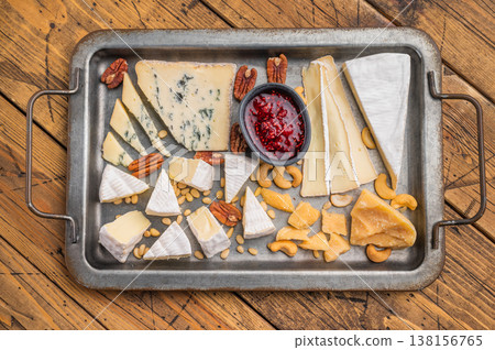 Selection of creamy Brie soft Camembert blue Roquefort and aged Parmesan served with nuts on a textured wooden background. 138156765
