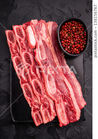 Premium raw short ribs (Kalbi style) and a meat fork on a black slate/stone surface, emphasizing quality and tools. Premium raw short ribs (Kalbi style) and a meat fork on a black slate/stone surface, emphasizing quality and tools. 138156767