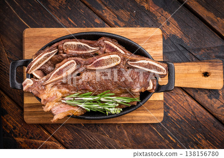 Grilled beef short ribs (Flanken/Galbi) with rosemary and garlic. Served on a wooden background with copy space. Grilled beef short ribs (Flanken/Galbi) with rosemary and garlic. Served on a wooden background with copy space. 138156780