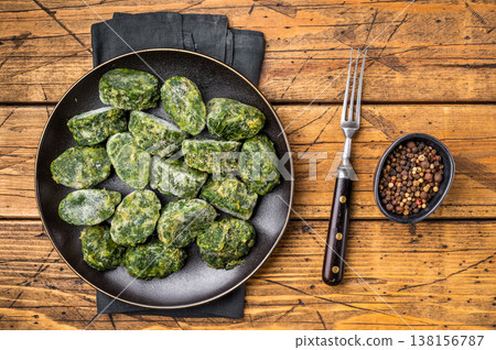 Frozen spinach blocks on a rustic black plate with a bowl of black pepper. Healthy raw vegetable ingredient on a wood table. Frozen spinach blocks on a rustic black plate with a bowl of black pepper. Healthy raw vegetable ingredient on a wood table. 138156787