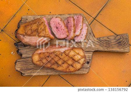 Tender seared duck breast sliced on wooden cutting board with bright tile backdrop great for cooking articles and stock marketplaces. Tender seared duck breast sliced on wooden cutting board with bright tile backdrop great for cooking articles and stock marketplaces. 138156792