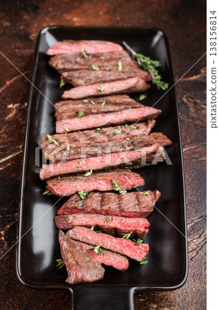 Sliced grilled beef steak served on black plate, juicy medium rare meat with clean presentation and copy space, gourmet restaurant style 138156814