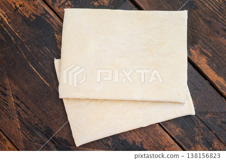 Raw puff pastry sheets stacked on wooden board, preparation ingredient for baking with copy space Raw puff pastry sheets stacked on wooden board, preparation ingredient for baking with copy space 138156823